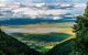 Elevated view of floor of Ngorongoro Crater from the southern edge of the crater. Looking toward Lerai Forest and the alkaline crater lake, Lake Magadi, with clouds covering the rim on other side.