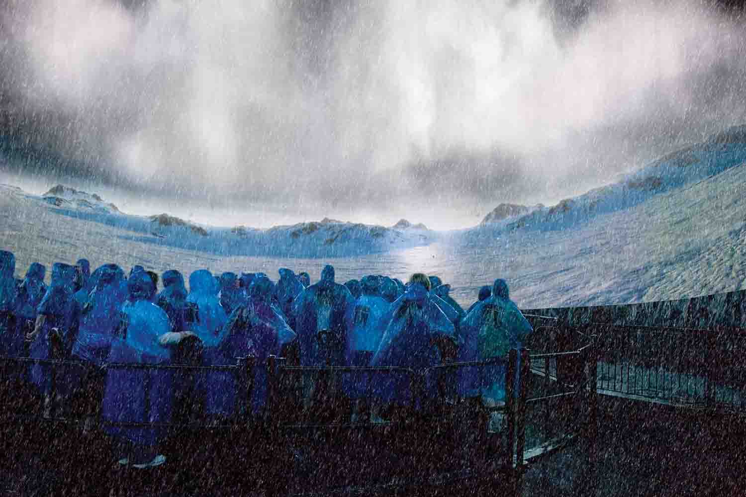 people huddled in raincoats inside the Niagara's Fury experience