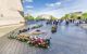 Tomb of an Unknown Soldier surrounded by flowers and placed just under Arc de Triomphe on a sunny day