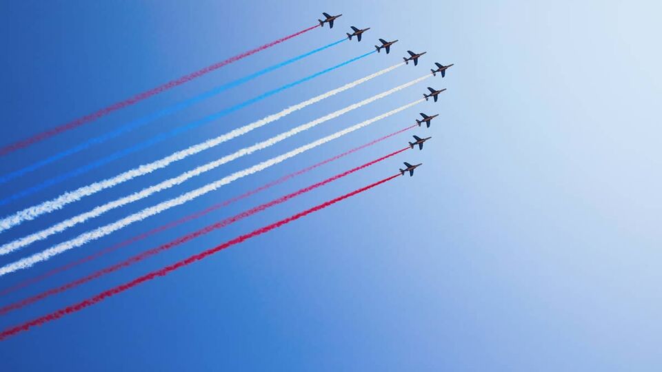 The French Air Force flying through the air spraying blue, white and red colours of the French flag