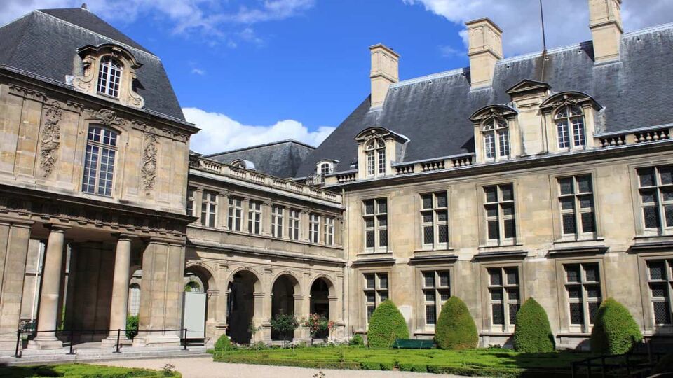 Courtyard with beautiful gardens of Carnavalet Museum on a sunny blue day