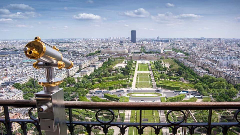 View of the open garden space and city from the balcony of the Eiffel Tower, with a telescope