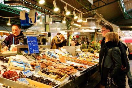 People buying fresh seafood at Marche des Enfants Rouges. Bright lights and a variety of seafood at this stall