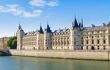 Landscape view of La Conciergerie building from across the river on a sunny blue day
