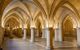 The Rayonnant gothic Hall of the Guards (Salle des Gens d’Armes) at the Conciergerie building in Paris. There are large arched shaped ceilings with lights illuminating the arches.