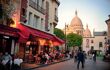 City street view of a street in Montmartre where there are restaurant diners sat outside before a sunset