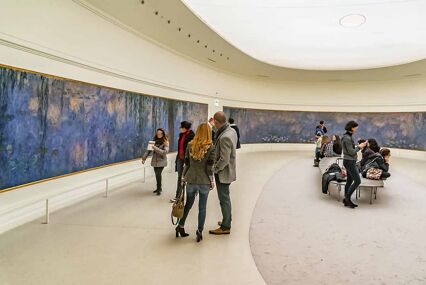 A white, curved room with Monet's oversized Water Lilly canvases wrapping around the entire room