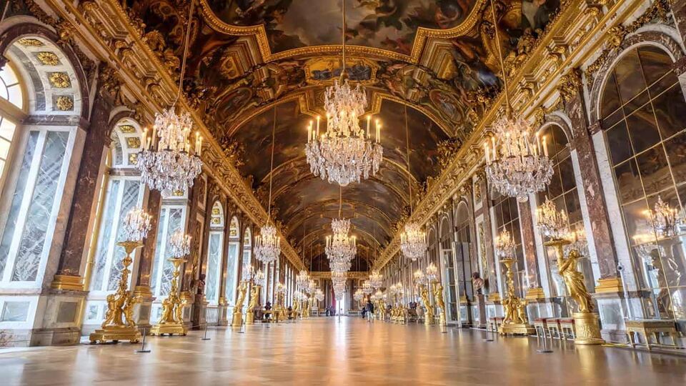 The Halls of Mirrors - Giant arch shaped mirrors covering the right wall with podiums of lit candles and sets of chandeliers hanging from the ceiling