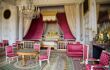 The Grand Trianon, a bedroom in Louis XIV style with pink and white coloured wall, chairs and railings.