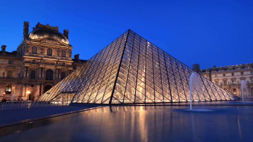 View of the Louvre Pyramid in the evening, illuminating with light from within the pyramid