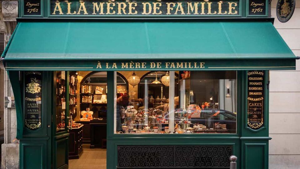 A classic vintage Paris candy store front À la Mère de Famille with Dark Green facade and appetizing samples in window