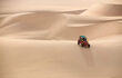A sand buggy descends a sand dune