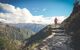 A hiker walking up a stony stepped pathway up the side of a mountain