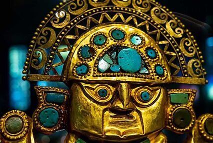 A golden sculpture of a face, with gemstones