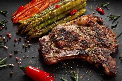 Rib Steak with Asparagus Carrots and Chilli Pepper on slate platter