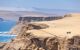 Two motorcycles stand on the edge of a cliff off the coast