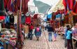 Sunday market in Pisac, people walk through the stalls on cobblestone road