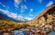 A river runs over rocks, with mountains rising either side