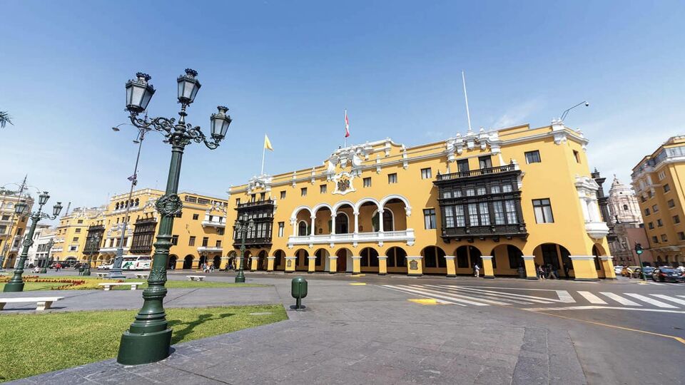 The pale yellow building of Municipal Palace of Lima seen from the other side of the plaza