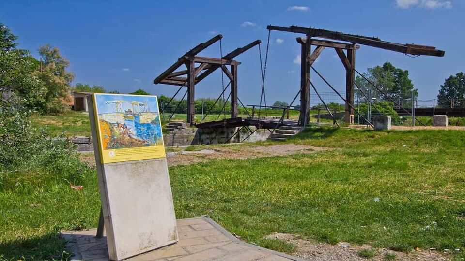 view of an old wooden bridge, with a van gogh information board in the foreground