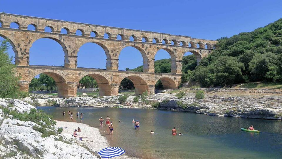 view of the aquaduct spanning the river, with people swimming below