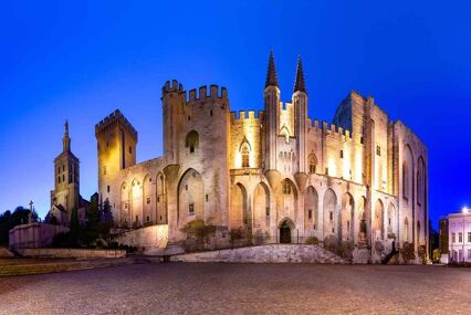 Exterior photo of the Palace of the Popes lit up at night