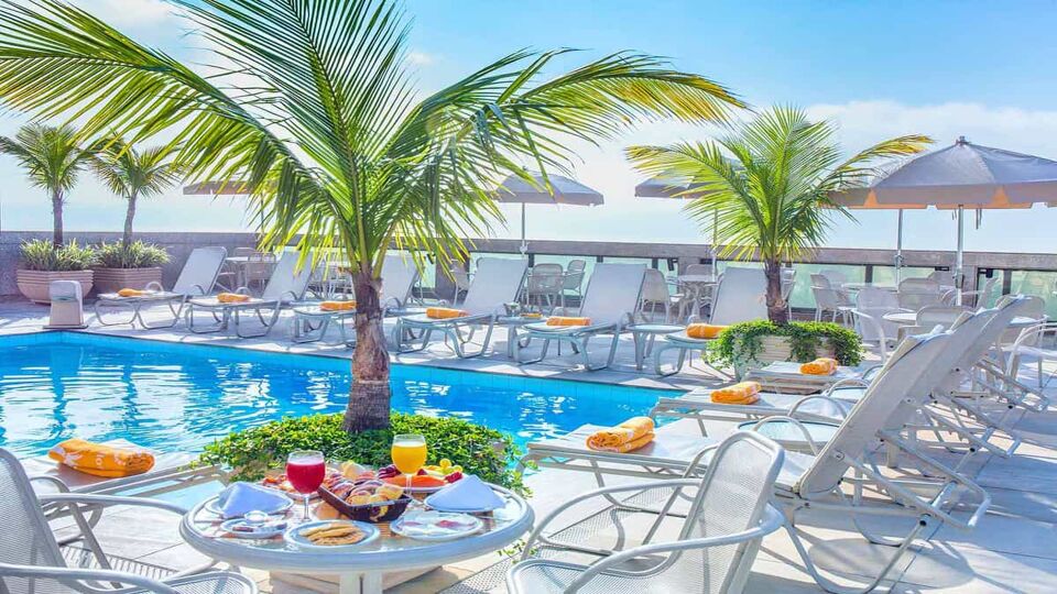 Hotel pool with palm trees and sea