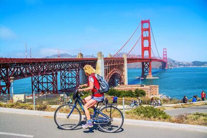 Girl cycling in front of the Golden Gate Bridge
