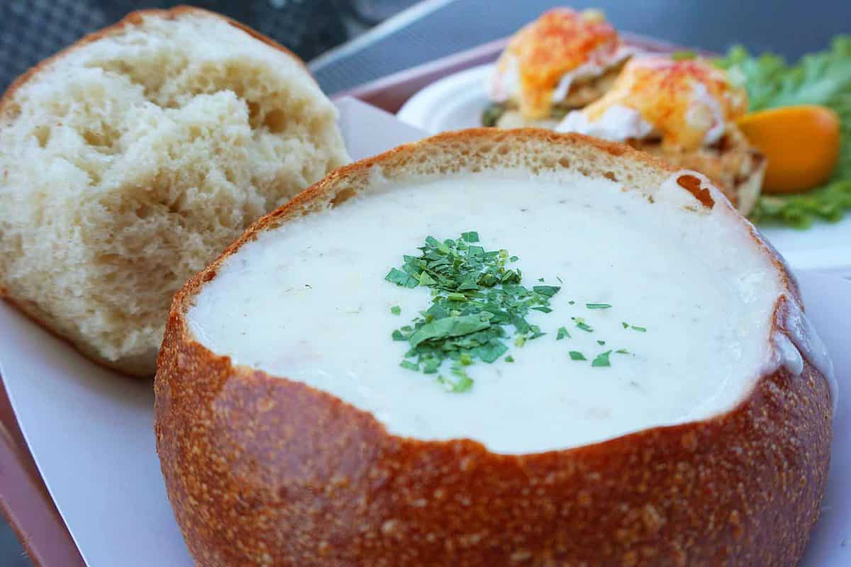 Closeup of clam chowder bread bowl and carb eggs benedict in an outdoor cafe
