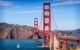 The Golden Gate Bridge, San Francisco, in late evening sun, with a sailing catamaran about to pass under into the bay..