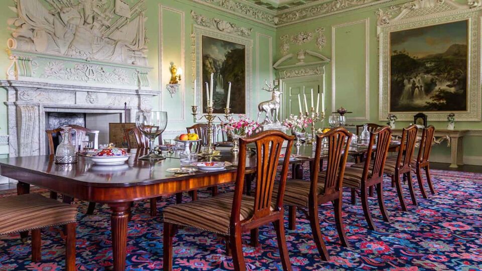 Ornate dining room with green walls and a dining table set for 12