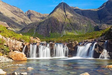 Lovely small waterfall with mountains behind on a sunny day