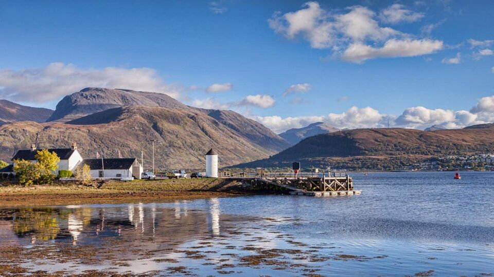 small hamlet in a peninsular sticking out into a lake, with Ben Nevis behind