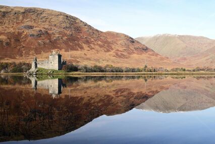 Ruins of Kilchurn Castle on the edge of Loch Awe with brown hills behind