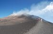 Tourist group climbing a path to the smoking Mt Etna, Sicily, Italy