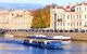 Boat tours the canals between large city buildings