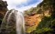 A narrow, tall waterfall on a sunny day.