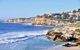 A rocky coastline with a beach, and houses.