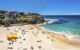 A photo of a picturesque beach with lots of people on it.