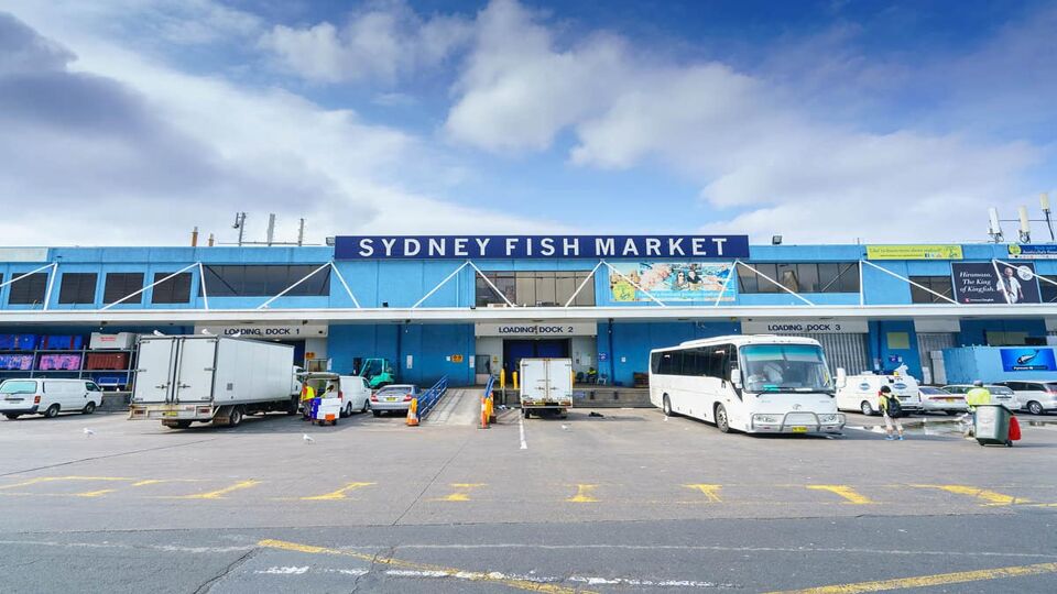 The exterior of the fish market with a coach in front of it.