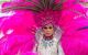 A close up of a person with a flamboyant pink headpiece and feathered pink wings.