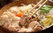 Close up of a hot pot containing chicken in broth