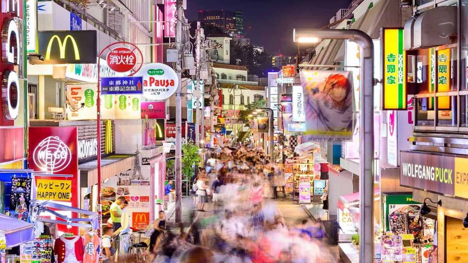 Crowds walk through Takeshita Street in the Harajuku district at night.