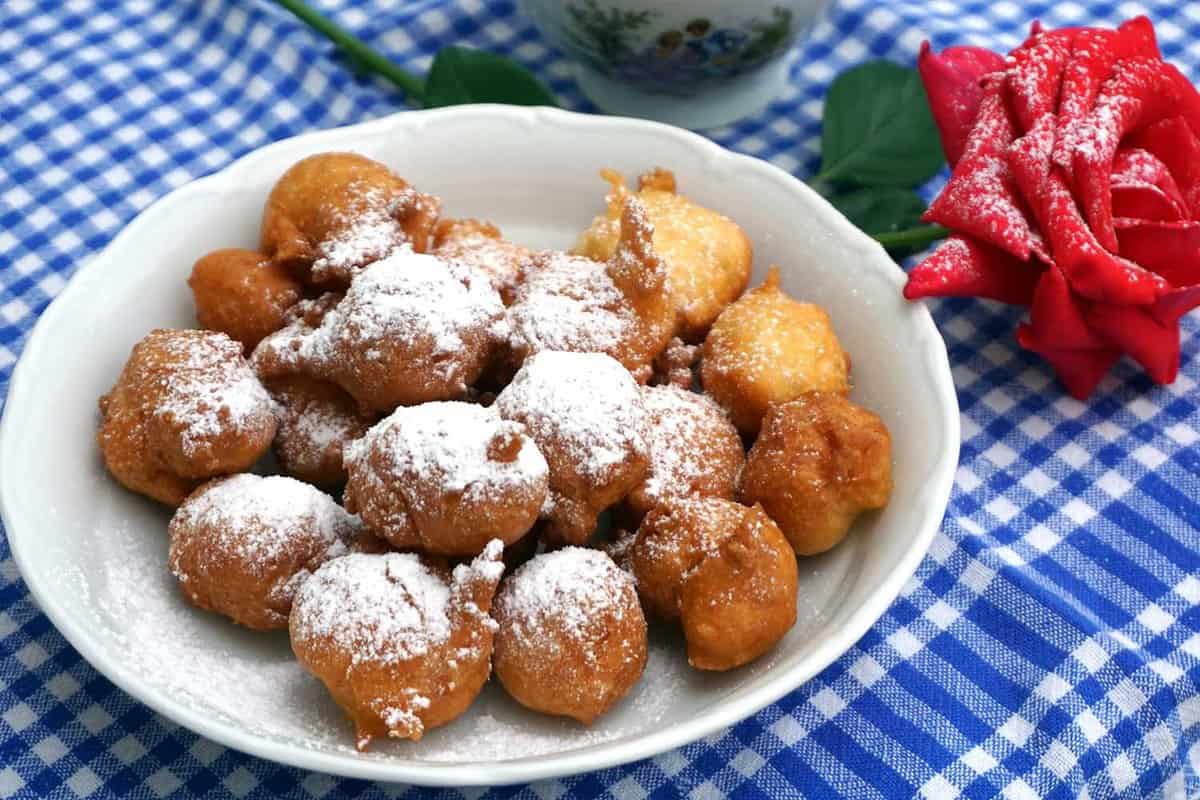 Sweet homemade fritter balls powdered with icing sugar and served on decorated table