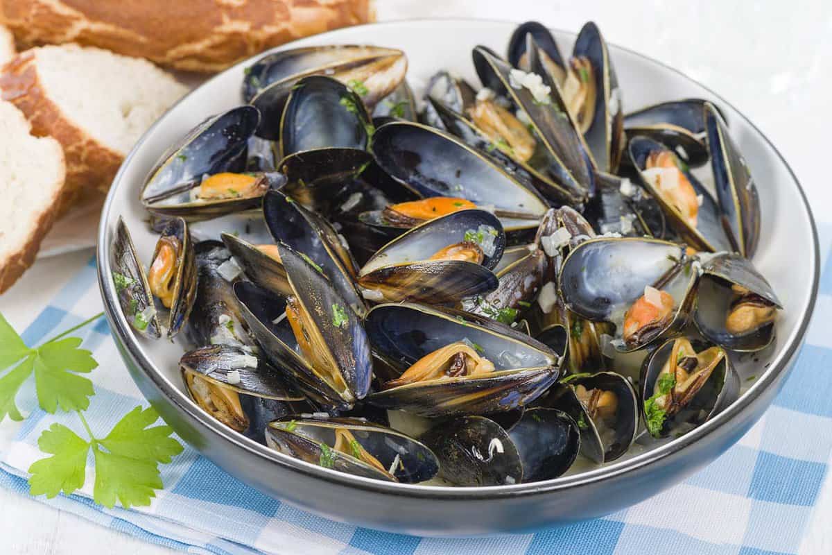 Mussels cooked with white wine sauce in a bowl with herbs