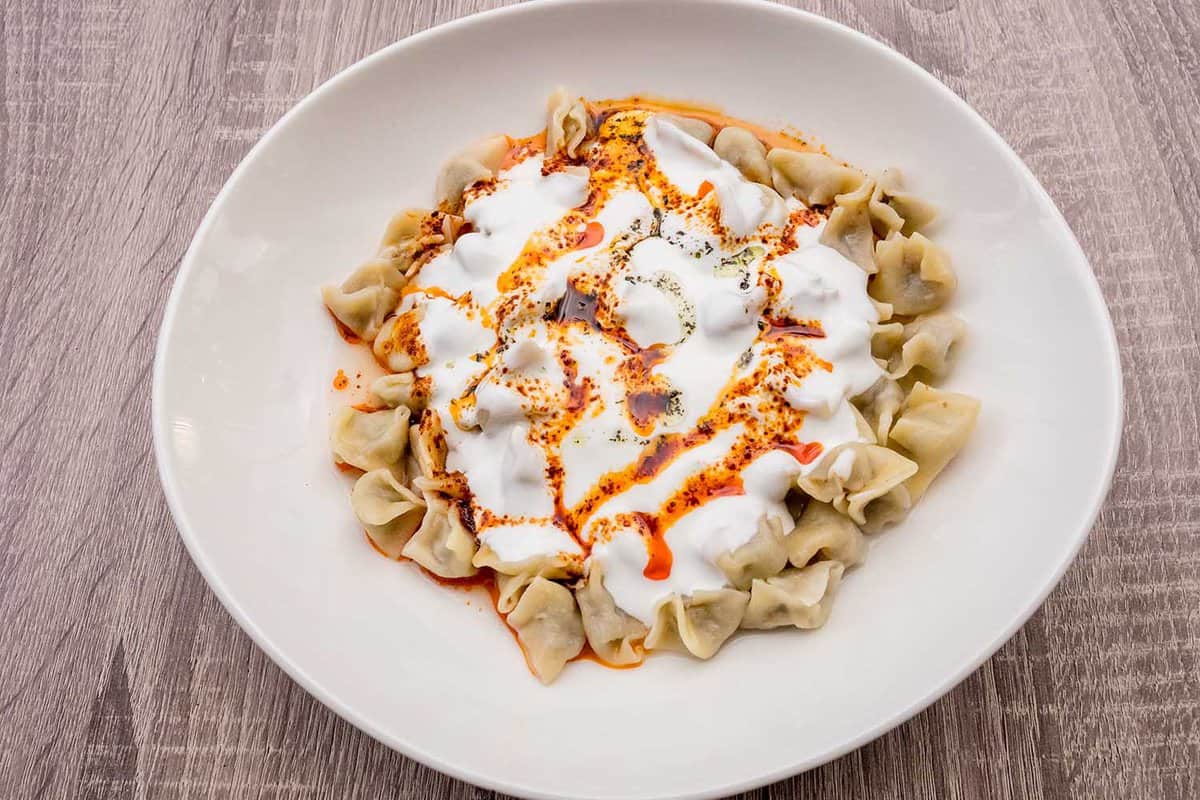 Turkish Manti with red pepper, tomato sauce, yogurt and mint. Plate of traditional Turkish food