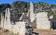 The ruins of an ancient building with a rocky hillside behind