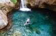 Man swimming in turquoise and crystal clear water near small waterfall in Sapadere canyon