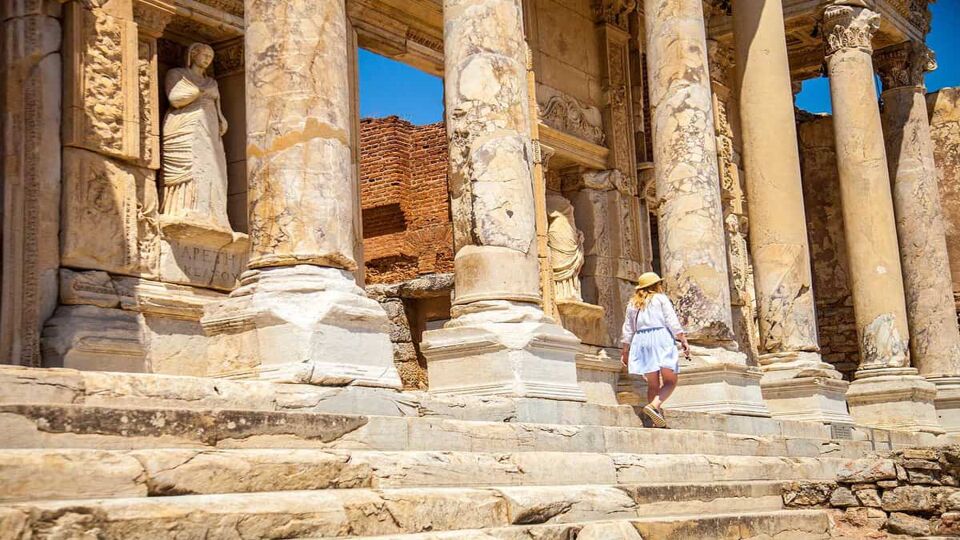 Female tourist walking at the foot of the Library of Celsus