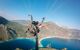 Paraglider flying above beach with a blue sky up ahead